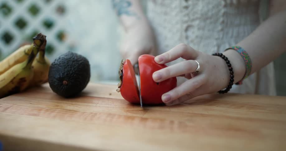 Woman stands outdoors slicing fruit on the chopping board