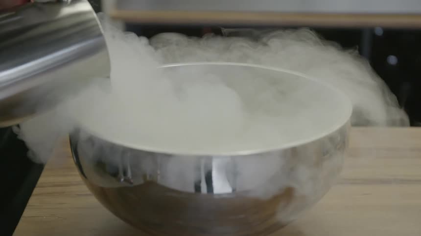 Liquid is being poured into a metal bowl making steam rise