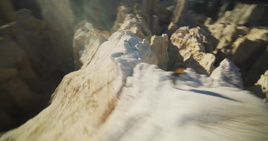 Person walks along ridge through rough terrain leading to plain
