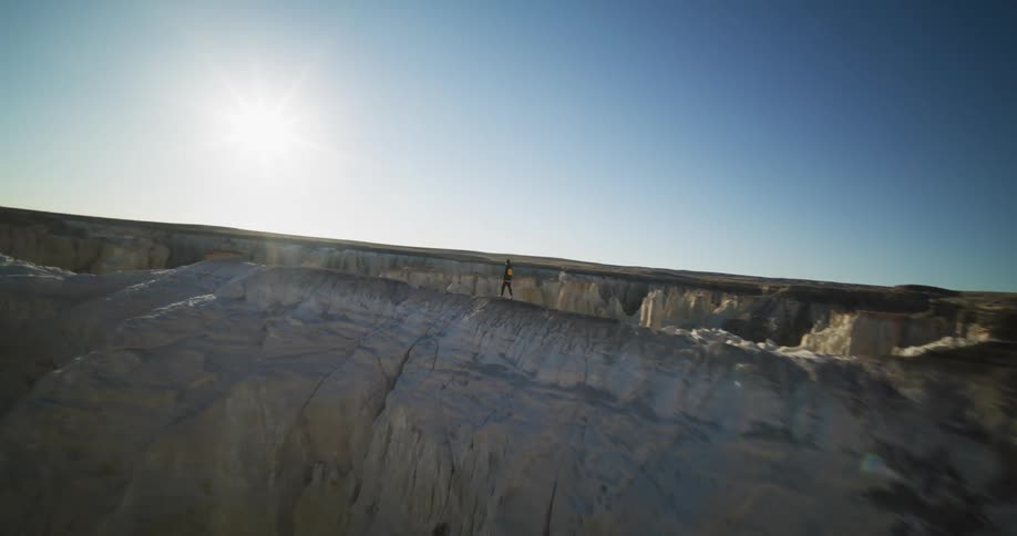 Hiker moves along ridge in rough mountainous terrain on a sunny day
