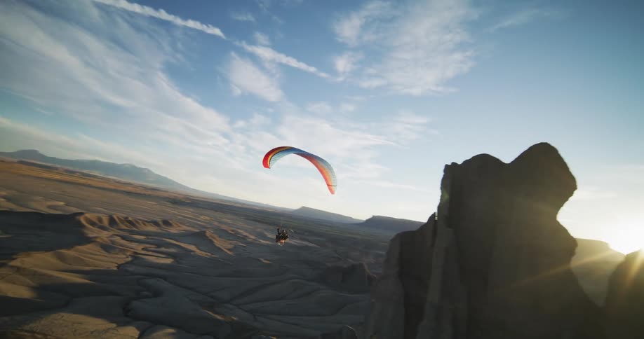 A person is gliding in a valley at dusk