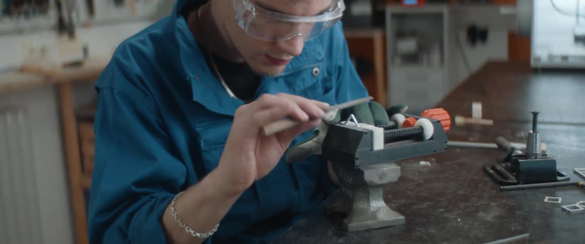 A man files down a three dimensional printed object in a lab