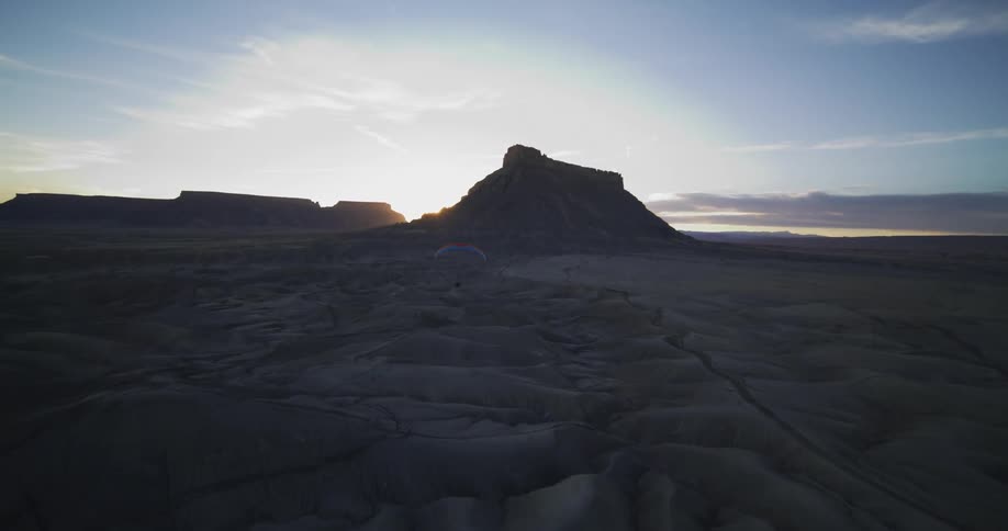 A person paraglides across a desert