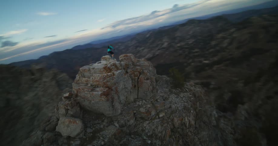 A woman hikes on a large stone cliff and climbs down