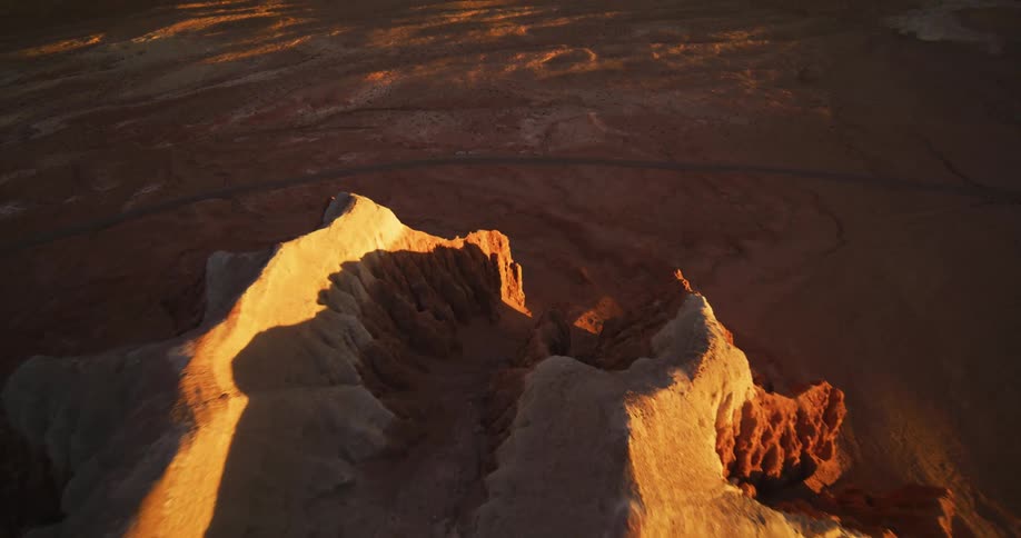 Sun shines across plains casting part of mountain ridge into shadow