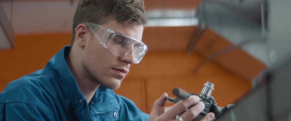 A man closely examines a device in a lab