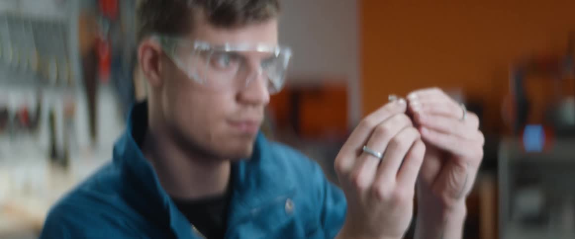 A man examines a metal ring closely in a workshop