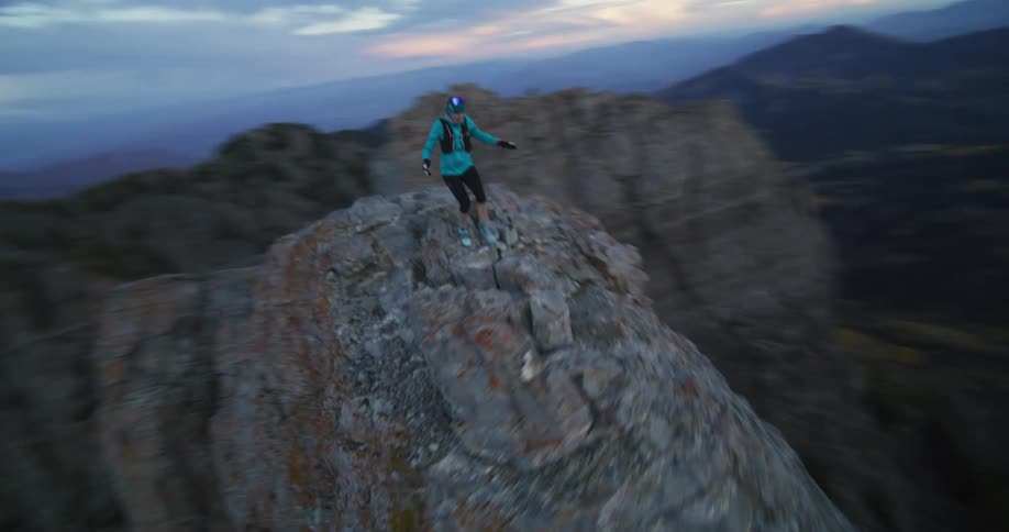 A woman wearing shorts is running along the top of a mountain ridge