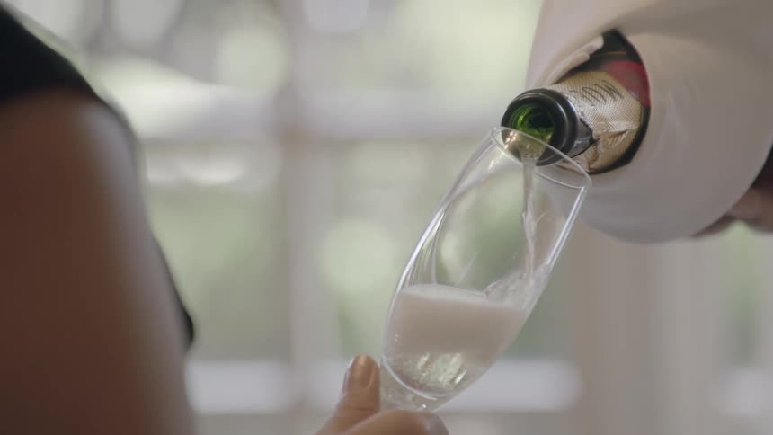Champagne being poured into a glass held by a woman
