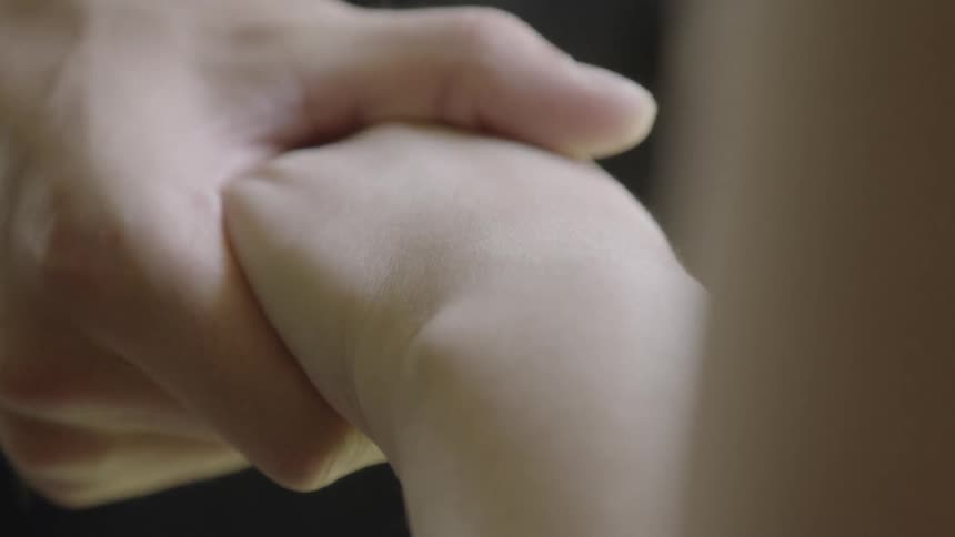 A hand is caressing and holding another