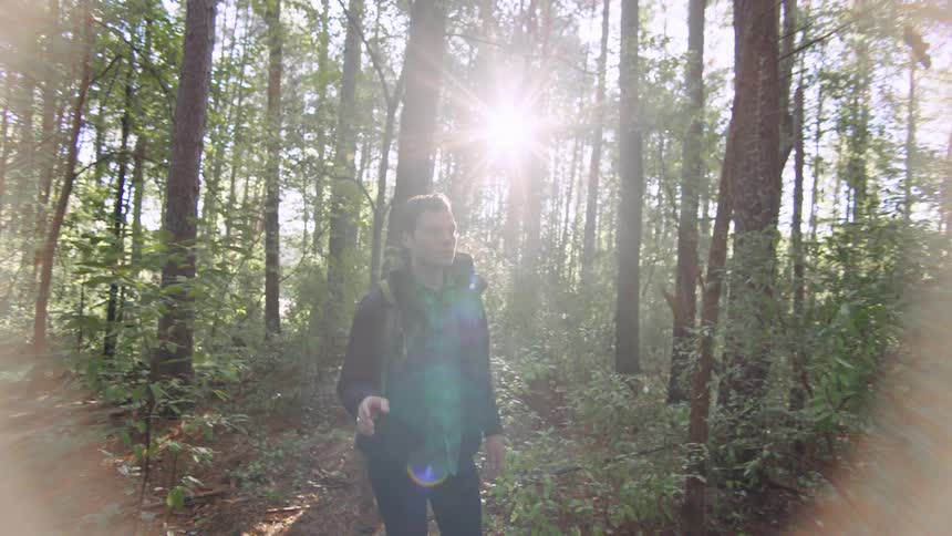 Young man hikes through woods