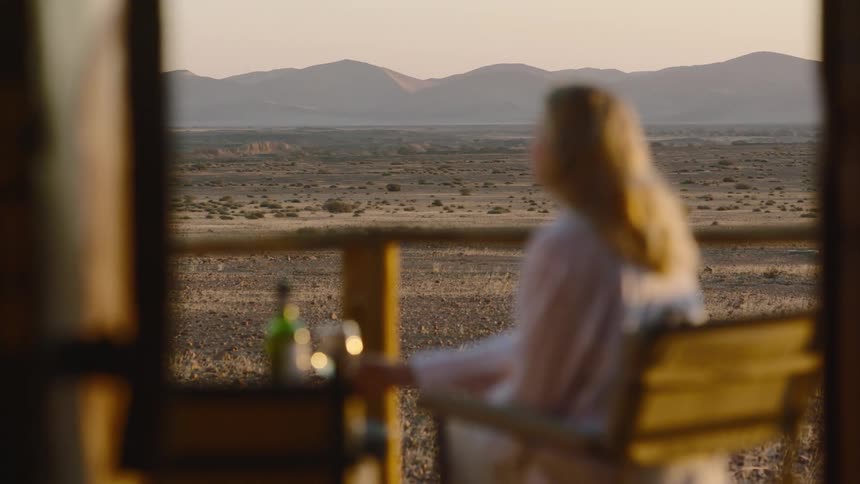 Young woman drinking wine in safari at sunset
