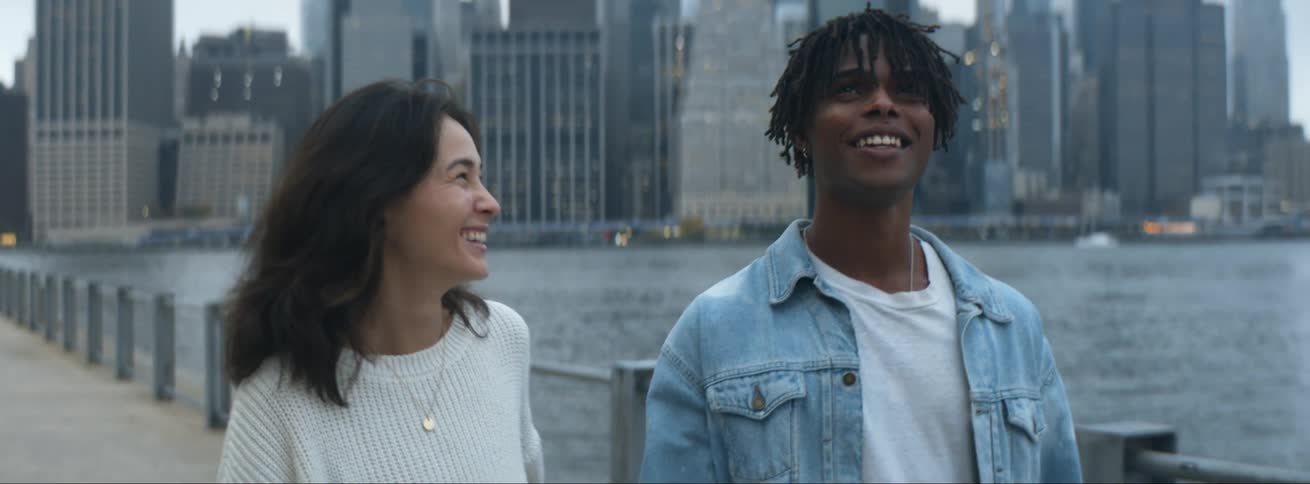 A man and woman walk near the shore of the city
