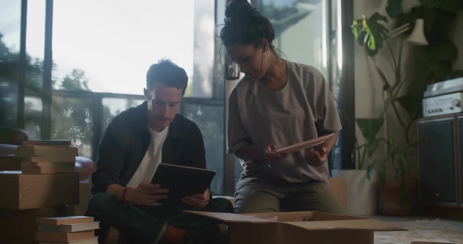 A woman unpacks as a man looks at a tablet