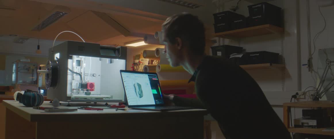 A man sitting down with a laptop inside a workplace