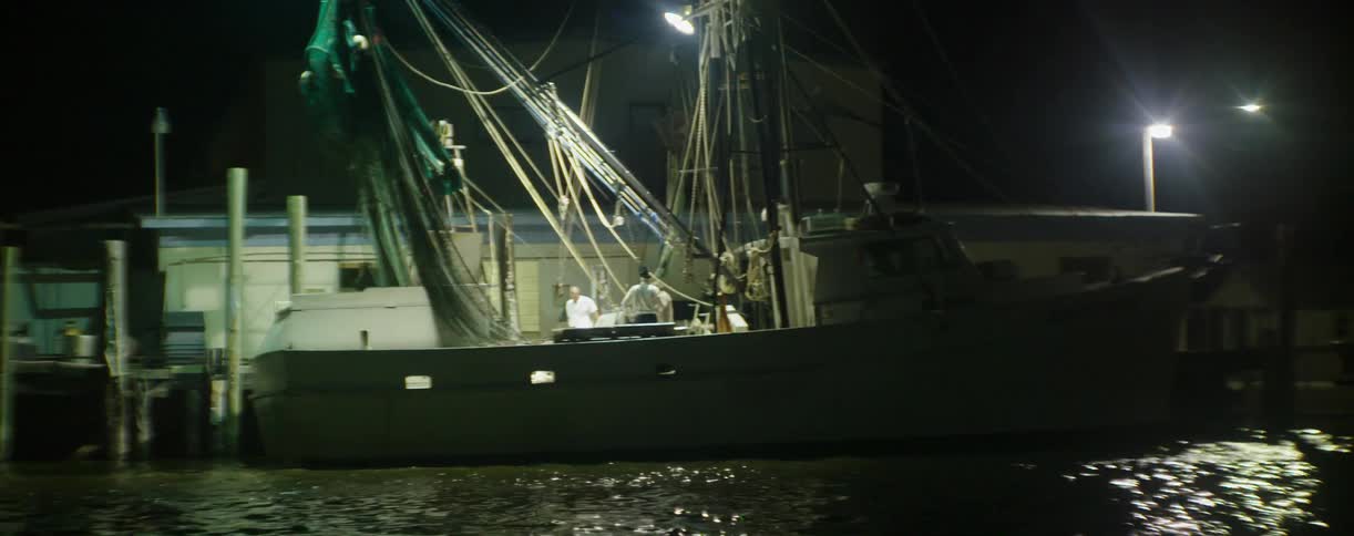 Men stand aboard a commercial ship docked at pier