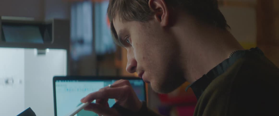 Man examines printed objects while standing near 3d printer and laptop