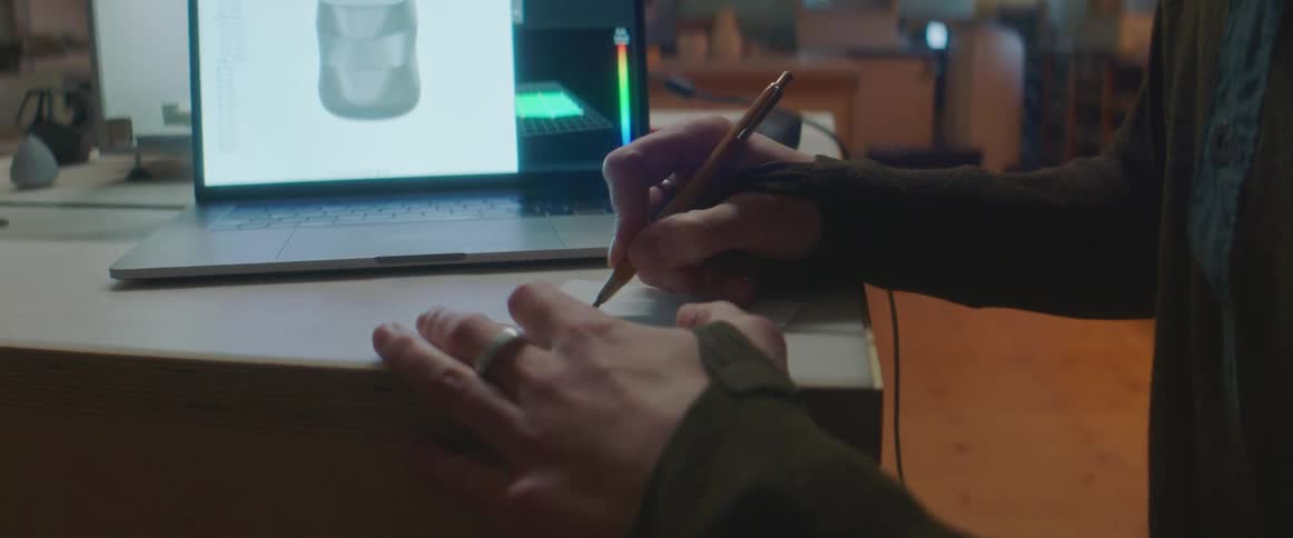 A person writing on a paper with a pencil