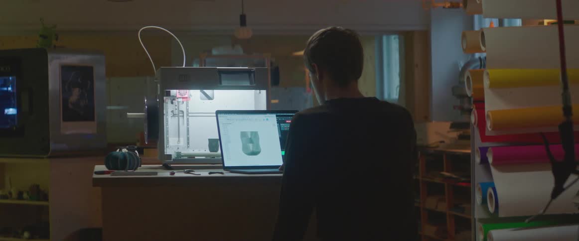 A man is sitting in front of a laptop and computer screen