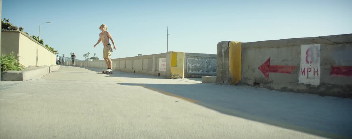 A man rides a skateboard down a road