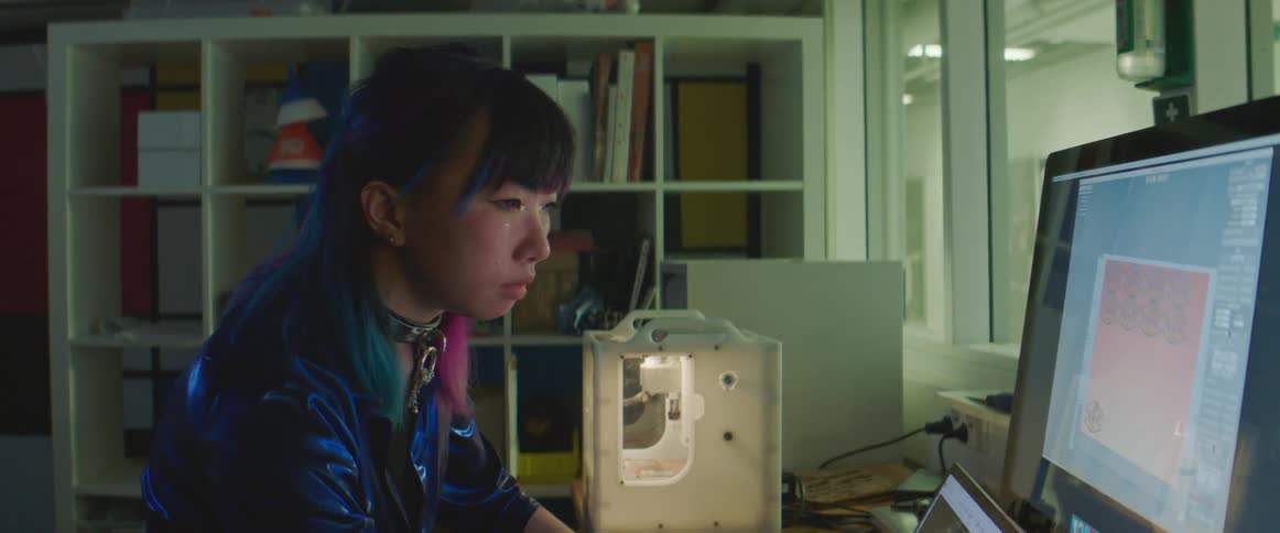 A young woman operates software on a computer at a desk indoors