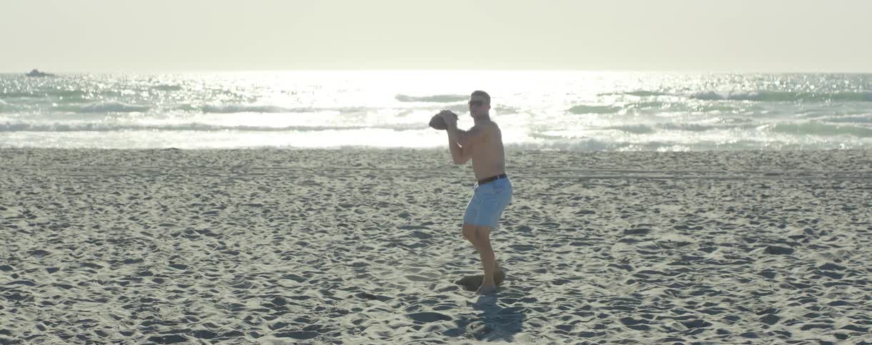 A man on the beach throws a football
