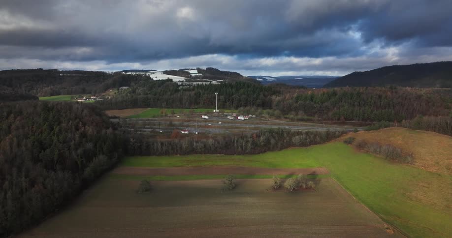 Aerial view of farmlands next to highway under clouds