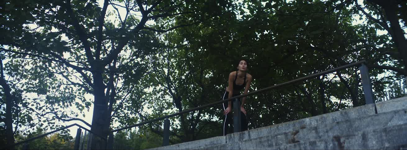 A young woman jogs up to a railing to catch her breath