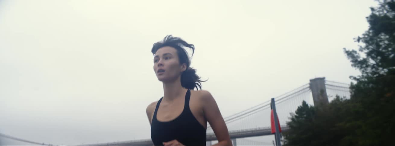 White woman wearing fitness jogging along the river at a big city