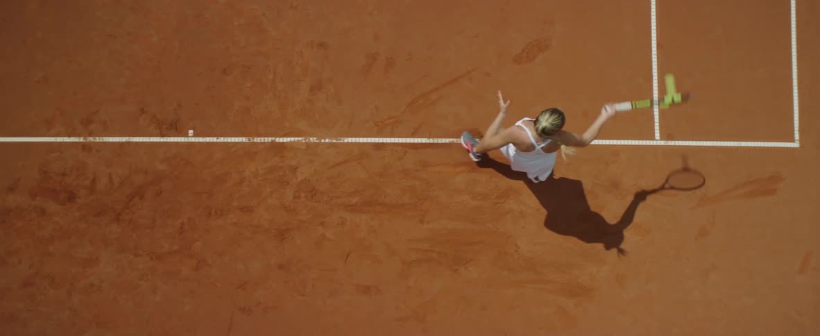 Blonde female tennis player with ponytail and white dress plays tennis in tennis court