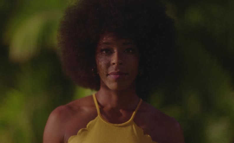 Woman wearing yellow stands outdoors posing and smiles