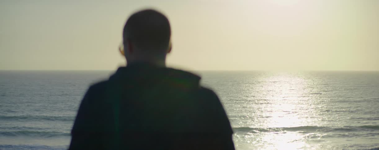 A man is standing overlooking the ocean at sunset