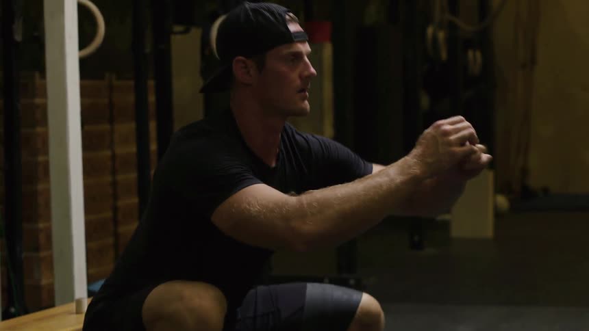 A man is crouched rocking back and forth