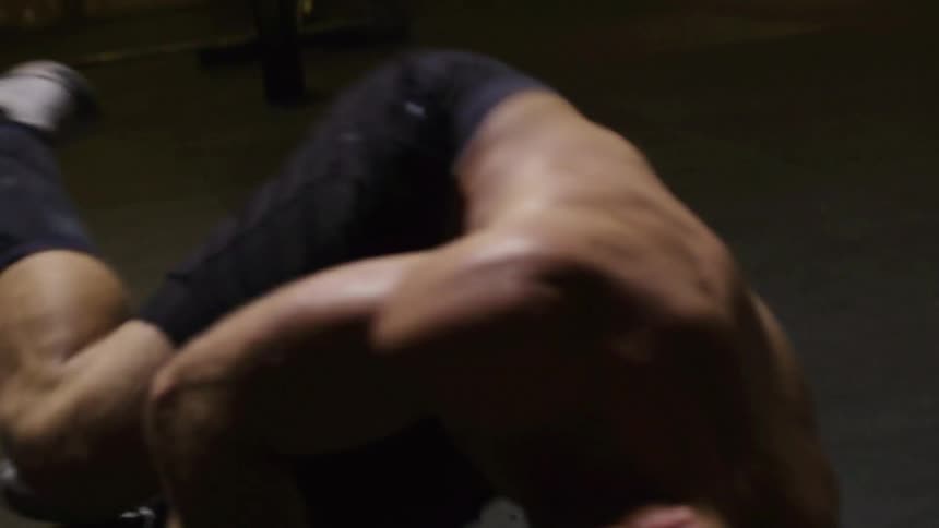 A man exercising on a rowing machine before rolling onto the floor