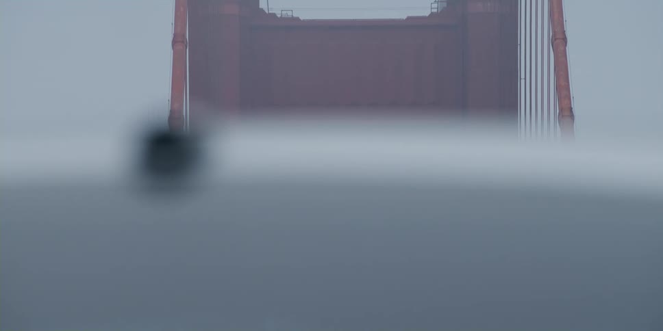 Vehicles and people walk by the large bridge