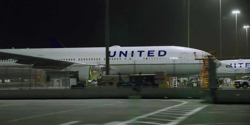 Air planes next to airport trucks and ladders at the airport at night