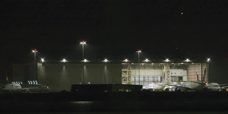 Jets at an airport hangar with bright lights at night