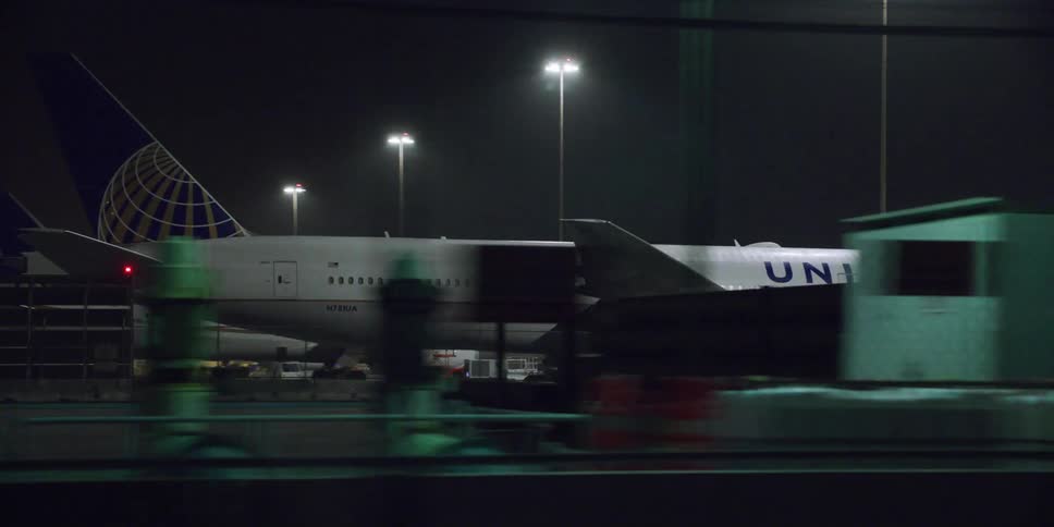 A plane is parked at an airport at night