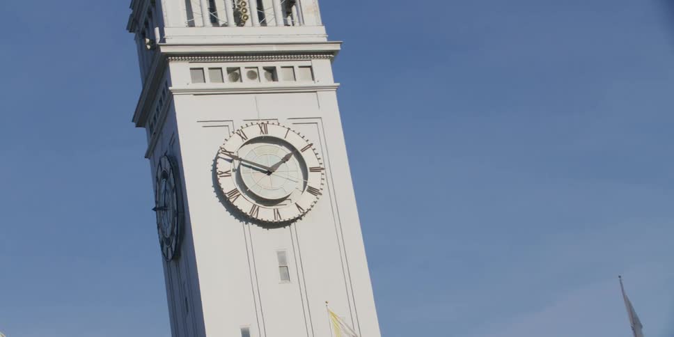 Clock tower sits on building against blue sky