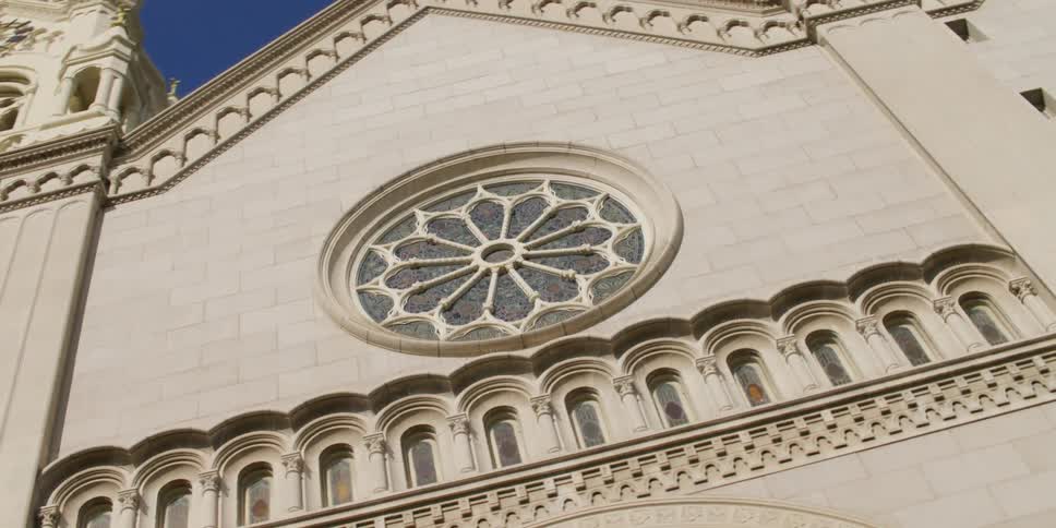 The round window of san franciscos saints peter and paul church under a bright blue sky