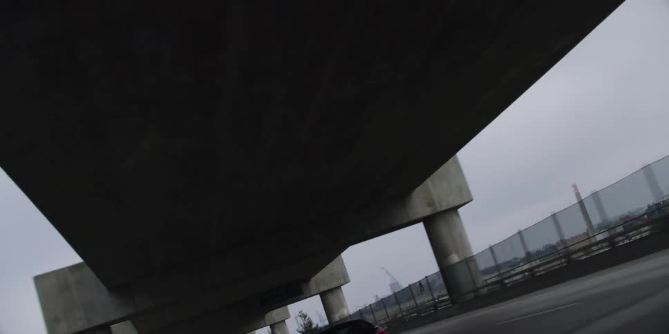 Sedan drives along highway under an overpass with fog covered skyline in the distance
