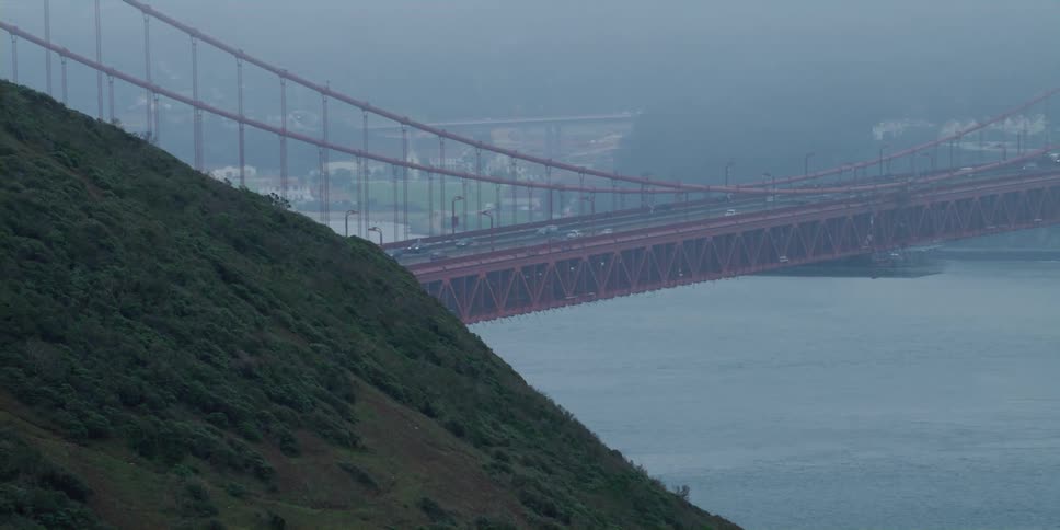 Distant view of vehicles crossing suspension bridge over river