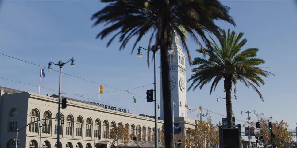 People gather near street outside building with a clock tower