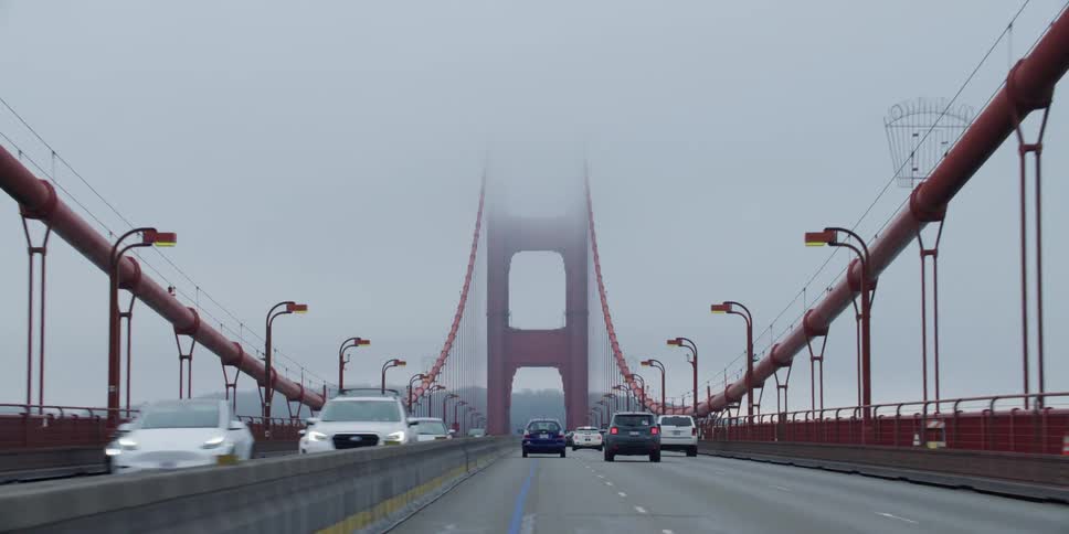 Automobiles are traveling across a suspension bridge