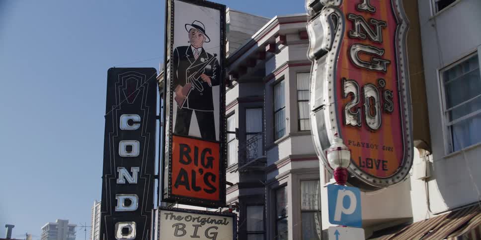 Vintage store signs hanging from the side of a small building in a city