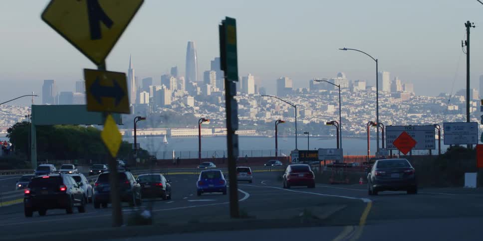 Cars are driving down a highway near a downtown city