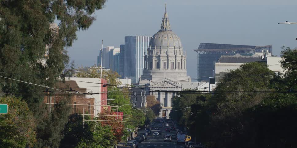 Vehicles move along street heading toward architecturally detailed domed building downtown