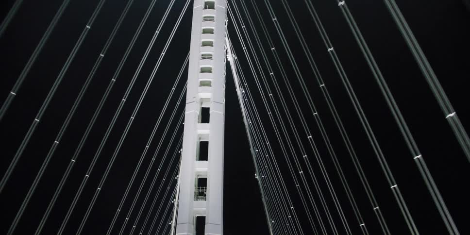 Traveling across a well lit suspension bridge at night in traffic