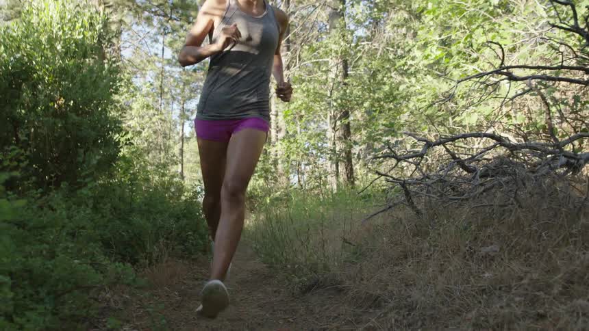 A woman jogging along a dirt path in the woods