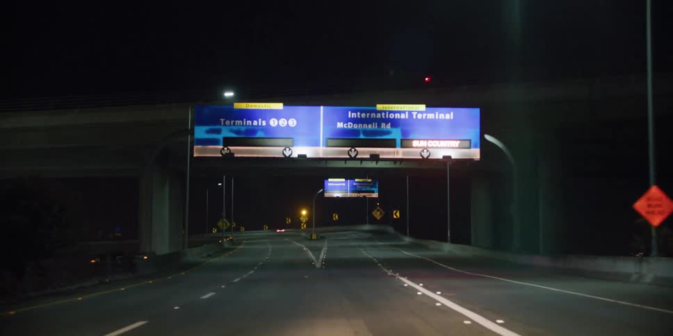 Sign over the highway signaling the entrance to an airport entrance